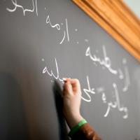 Student writes in Arabic on a chalkboard