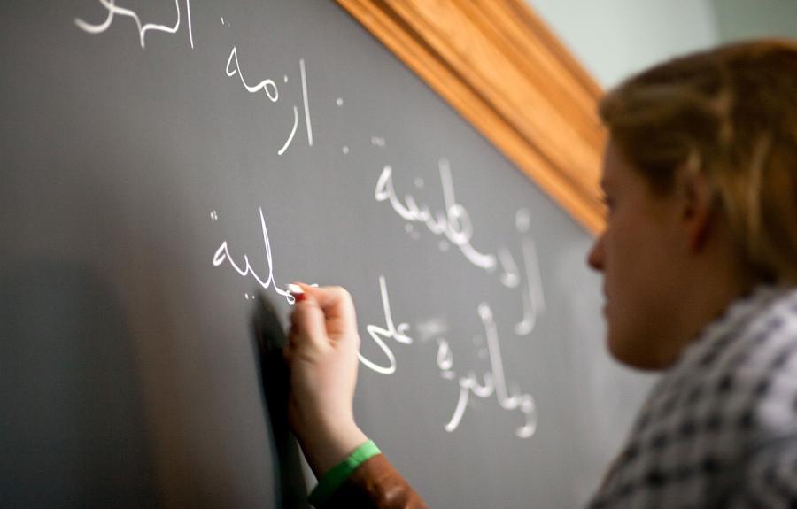 Student writes in Arabic on a chalkboard