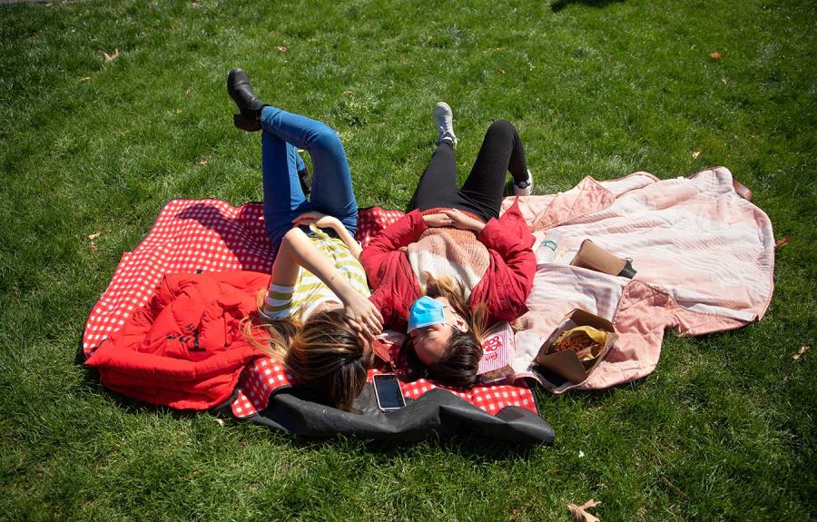 Students laying on a blanket enjoying the sunshine