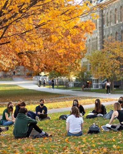 Students sit in a cirlce outside for class